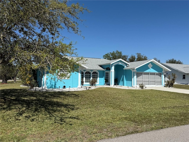 ranch-style house with a garage, driveway, a front lawn, and stucco siding