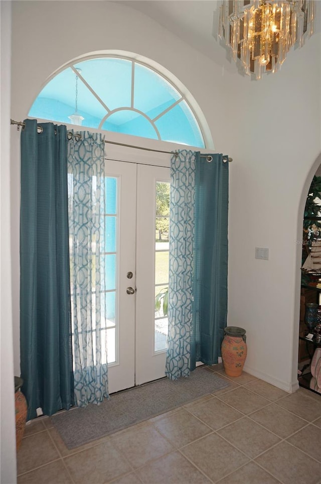 entrance foyer featuring tile patterned flooring, french doors, an inviting chandelier, and arched walkways