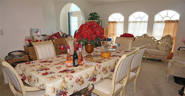 carpeted dining area featuring arched walkways