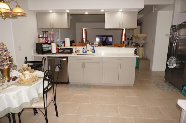 kitchen featuring light countertops, dishwashing machine, a peninsula, freestanding refrigerator, and a sink