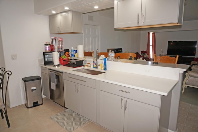 kitchen with a sink, dishwasher, a peninsula, and light countertops