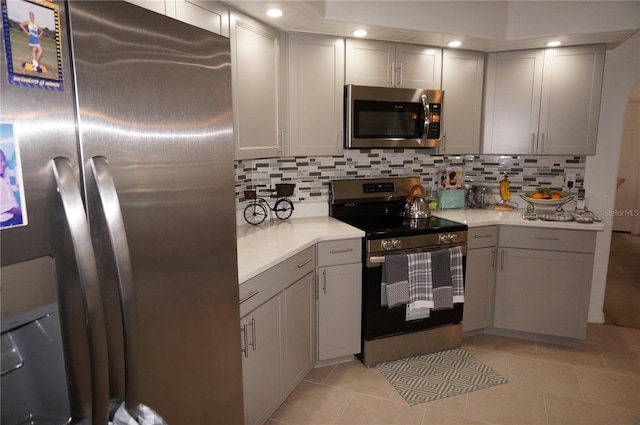 kitchen featuring light tile patterned floors, backsplash, stainless steel appliances, and light countertops