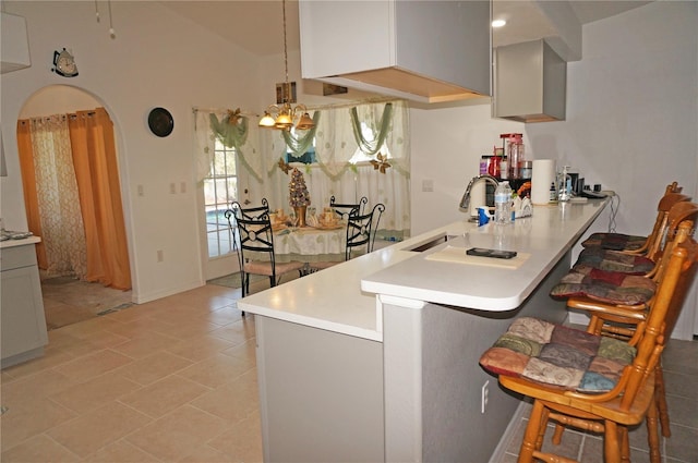 kitchen with arched walkways, a kitchen breakfast bar, light countertops, and a peninsula