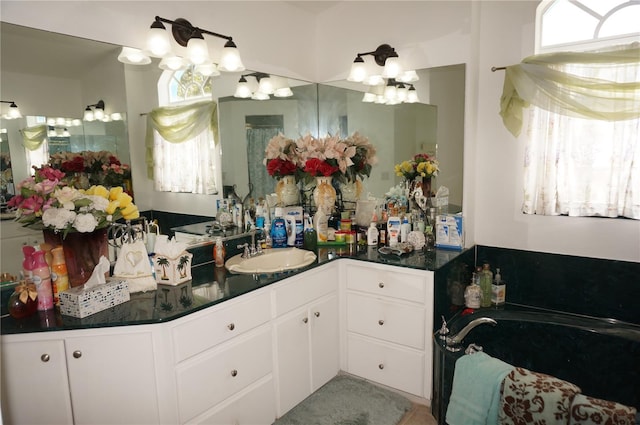 bathroom with a bath, a chandelier, a healthy amount of sunlight, and vanity