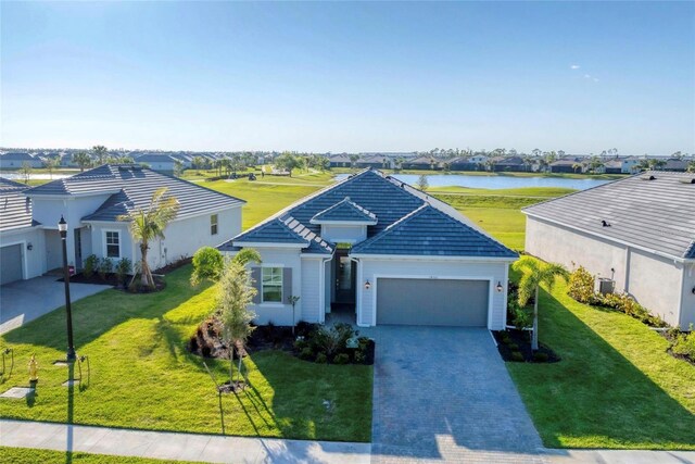 14381 Heritage Landing Blvd, Punta Gorda, FL 33955 - ranch-style home featuring a front lawn, a water view, a tiled roof, decorative driveway, and an attached garage