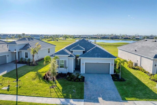 14381 Heritage Landing Blvd, Punta Gorda, FL 33955 - single story home with a water view, a front lawn, a tile roof, decorative driveway, and a garage