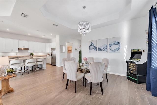 14381 Heritage Landing Blvd, Punta Gorda, FL 33955 - dining area with a tray ceiling, a notable chandelier, visible vents, and light wood finished floors