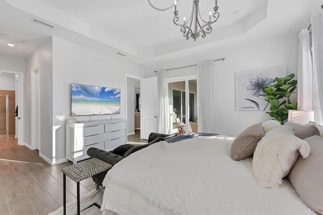 14381 Heritage Landing Blvd, Punta Gorda, FL 33955 - bedroom featuring visible vents, a raised ceiling, wood finished floors, an inviting chandelier, and baseboards
