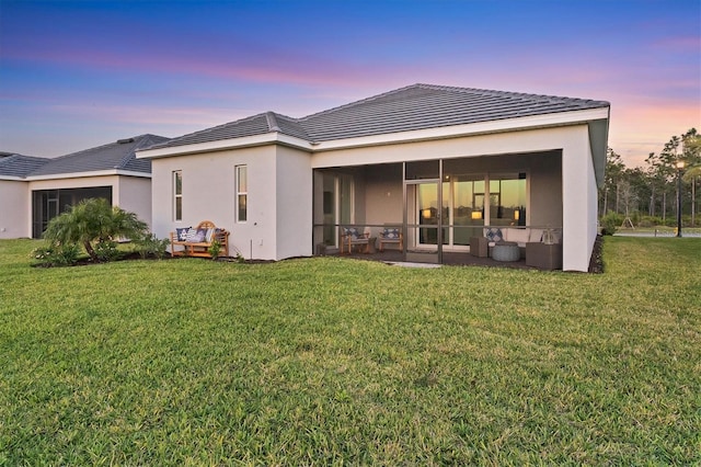 14381 Heritage Landing Blvd, Punta Gorda, FL 33955 - back of house with stucco siding, a lawn, a tiled roof, and a sunroom