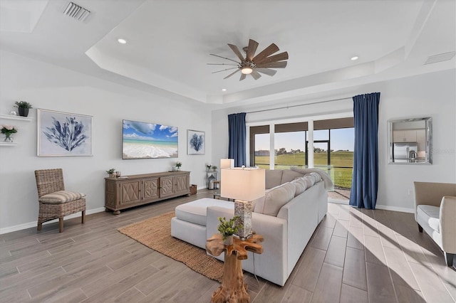 14381 Heritage Landing Blvd, Punta Gorda, FL 33955 - living room with wood finish floors, visible vents, a tray ceiling, baseboards, and ceiling fan