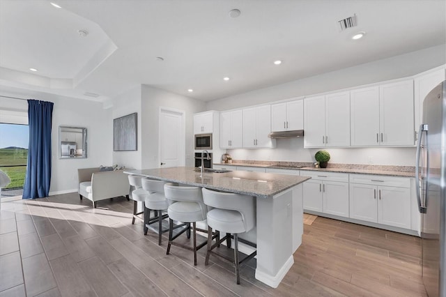 14381 Heritage Landing Blvd, Punta Gorda, FL 33955 - kitchen with visible vents, under cabinet range hood, appliances with stainless steel finishes, white cabinets, and wood tiled floor