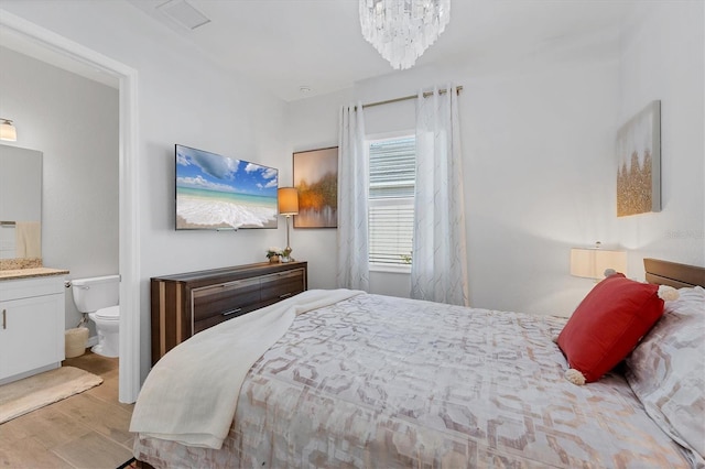 14381 Heritage Landing Blvd, Punta Gorda, FL 33955 - bedroom featuring a notable chandelier, visible vents, ensuite bath, and wood finished floors