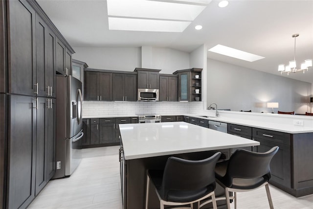 kitchen featuring lofted ceiling with skylight, backsplash, a peninsula, and stainless steel appliances