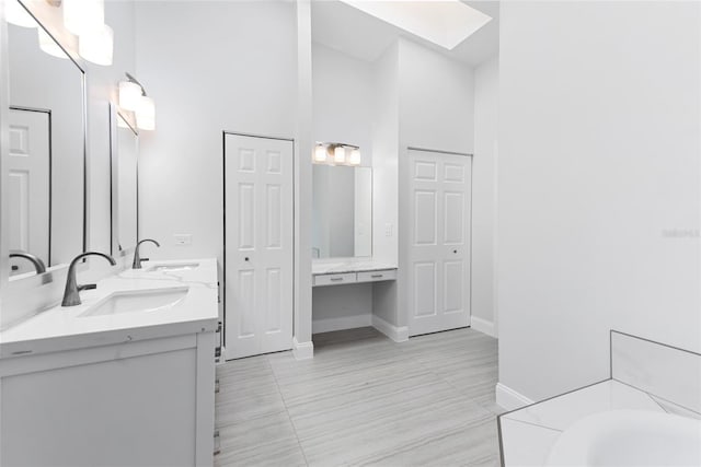 bathroom featuring a sink, a skylight, double vanity, and a bath