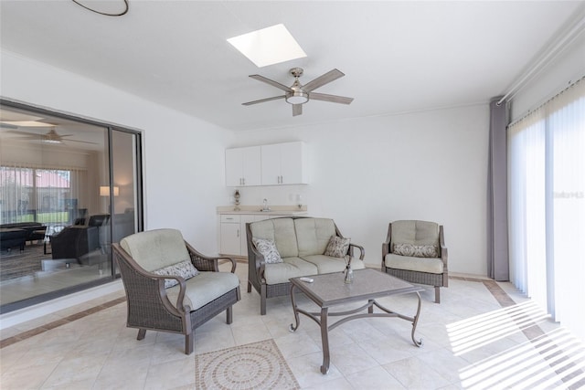 sitting room with light tile patterned floors, a skylight, and a ceiling fan