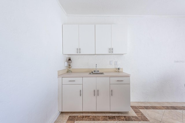 bar featuring a sink, crown molding, and a textured wall