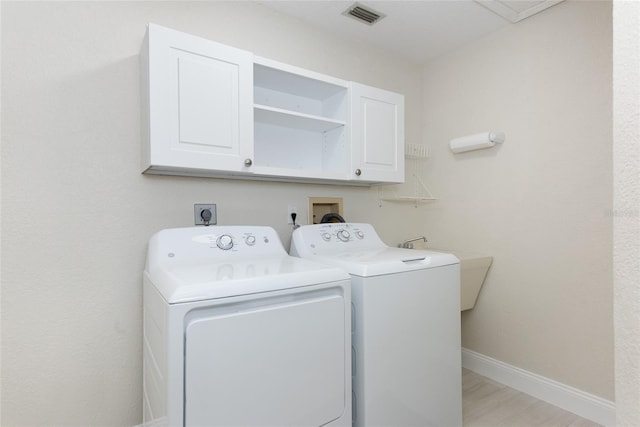 laundry room with visible vents, baseboards, cabinet space, washer and dryer, and light wood-type flooring