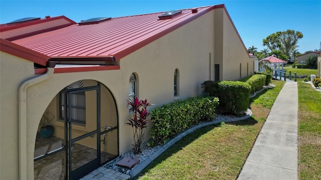 view of property exterior featuring a yard, stucco siding, metal roof, and a standing seam roof