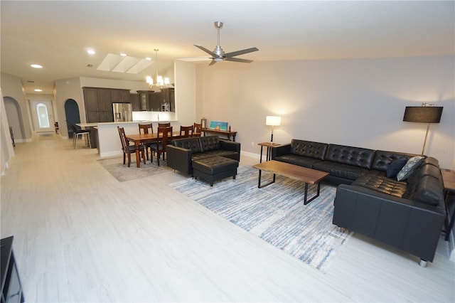 living area with baseboards, light wood-type flooring, recessed lighting, ceiling fan with notable chandelier, and arched walkways