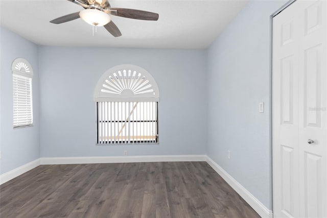 empty room with ceiling fan, dark wood-type flooring, and baseboards