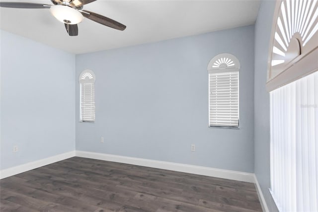 spare room featuring a healthy amount of sunlight, baseboards, dark wood-style flooring, and ceiling fan