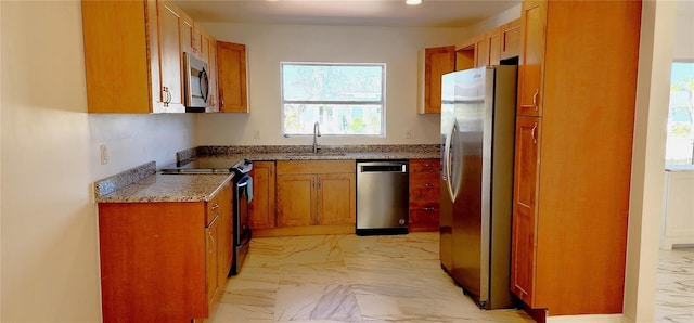 3372 Elkcam Blvd, Port Charlotte, FL 33952 - kitchen with light stone countertops, brown cabinetry, a sink, appliances with stainless steel finishes, and marble finish floor