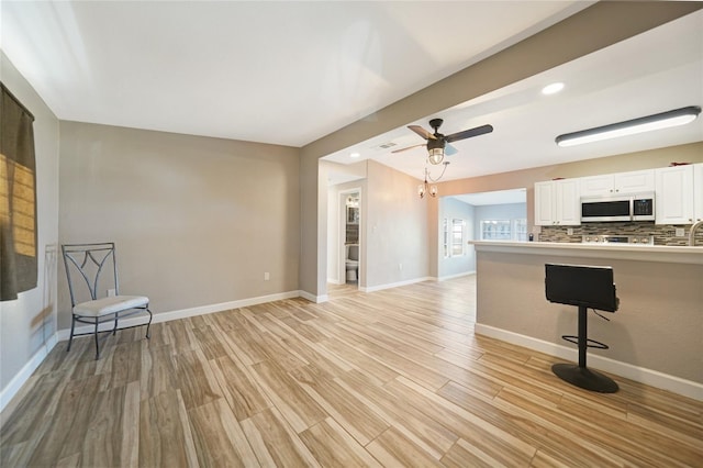 unfurnished living room with recessed lighting, light wood-style flooring, a ceiling fan, and baseboards