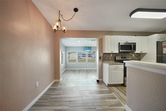 kitchen with baseboards, an inviting chandelier, decorative backsplash, white cabinets, and appliances with stainless steel finishes