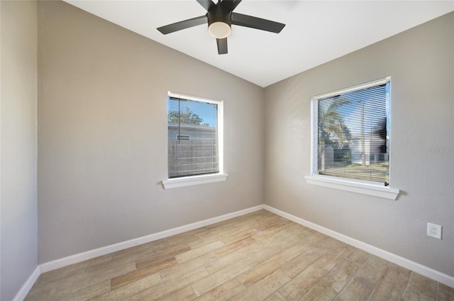 unfurnished room with vaulted ceiling, plenty of natural light, wood finished floors, and baseboards