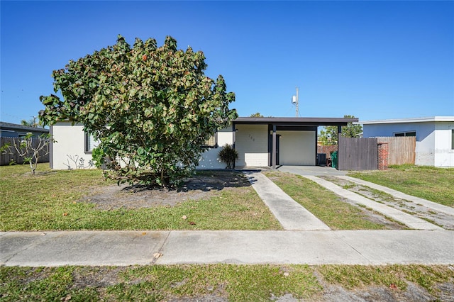 view of front of property featuring stucco siding, a front lawn, fence, concrete driveway, and an attached carport