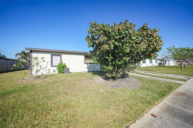 view of front facade with a front yard, fence, and stucco siding