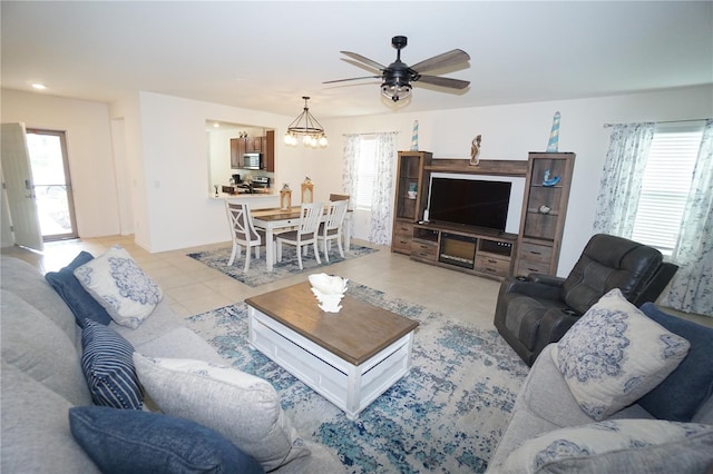 living area with light tile patterned floors and ceiling fan with notable chandelier
