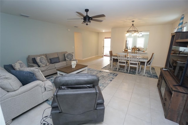 living area with light tile patterned floors, visible vents, baseboards, and ceiling fan with notable chandelier