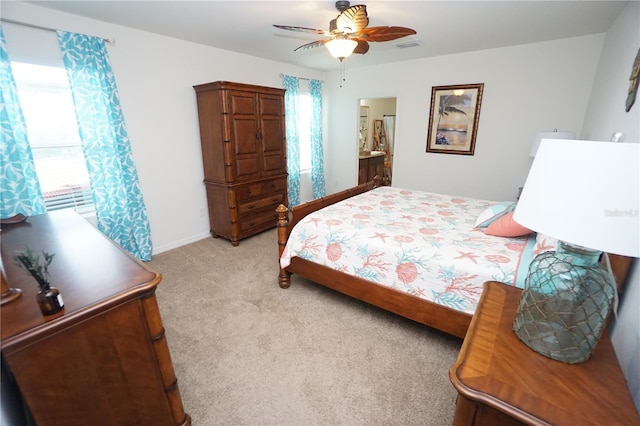 bedroom with connected bathroom, baseboards, light colored carpet, and a ceiling fan