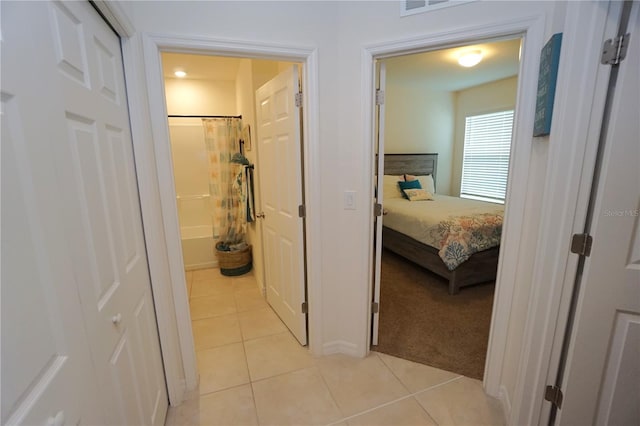 hallway with light tile patterned floors and light carpet