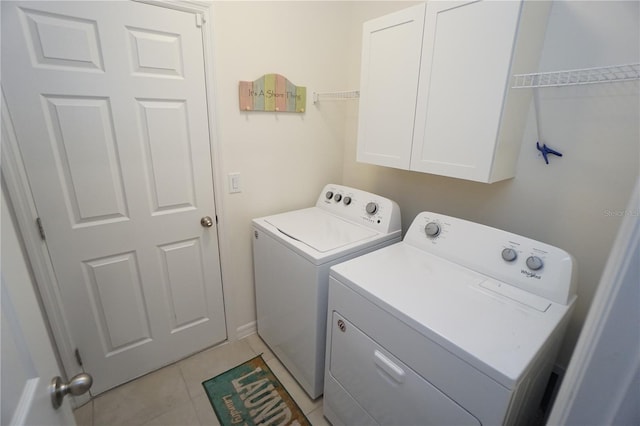 washroom featuring light tile patterned flooring, cabinet space, and washing machine and clothes dryer