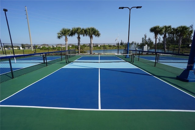 view of tennis court with community basketball court and fence