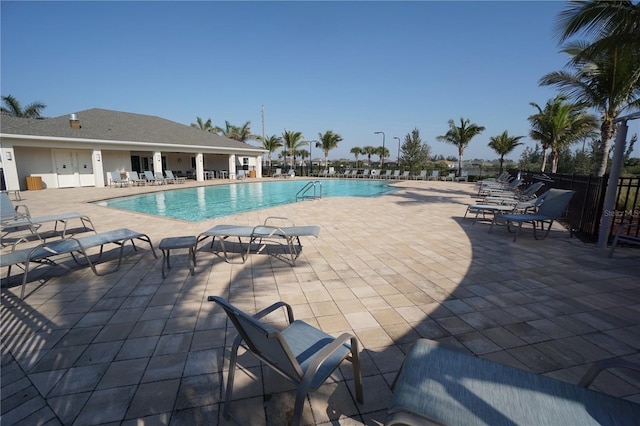 community pool with a patio area and fence