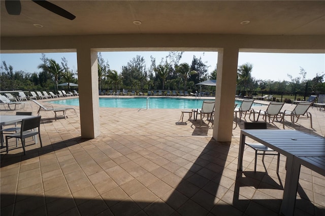 community pool with a patio area and fence
