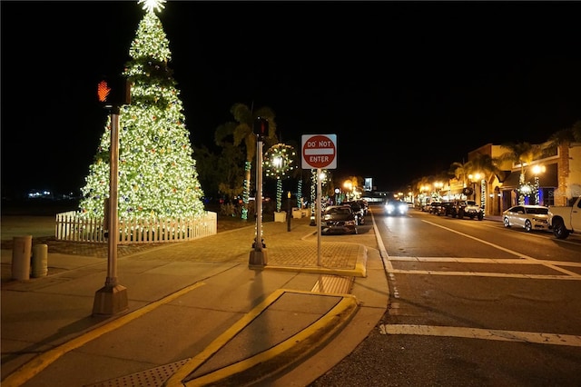 view of road featuring sidewalks, curbs, street lights, and traffic signs