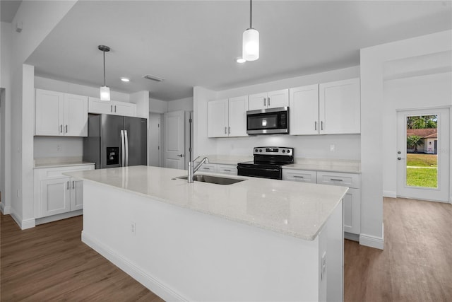 kitchen with dark wood finished floors, a sink, hanging light fixtures, white cabinets, and appliances with stainless steel finishes