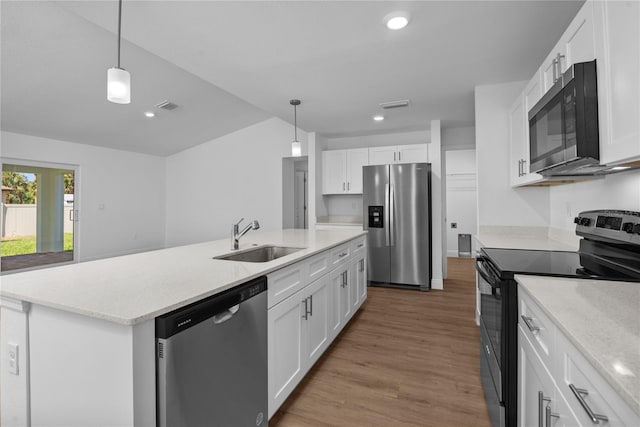 kitchen featuring appliances with stainless steel finishes, wood finished floors, hanging light fixtures, white cabinets, and a sink