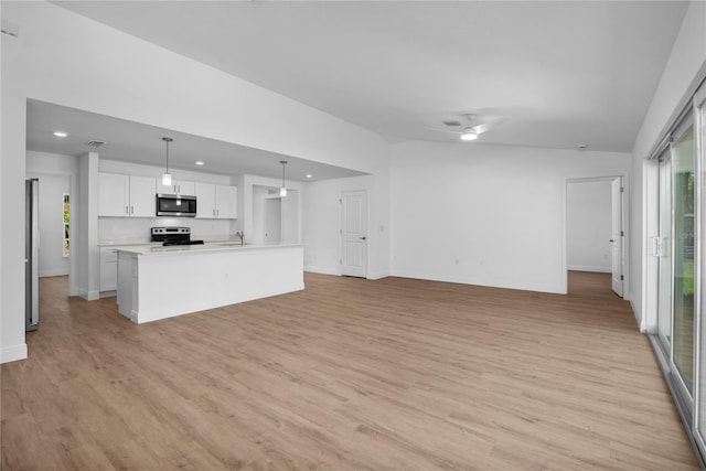 kitchen featuring open floor plan, light wood-style flooring, white cabinets, stainless steel appliances, and a sink