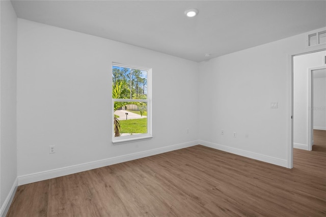 spare room featuring visible vents, baseboards, and wood finished floors