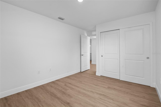 unfurnished bedroom with a closet, visible vents, baseboards, and light wood-style floors