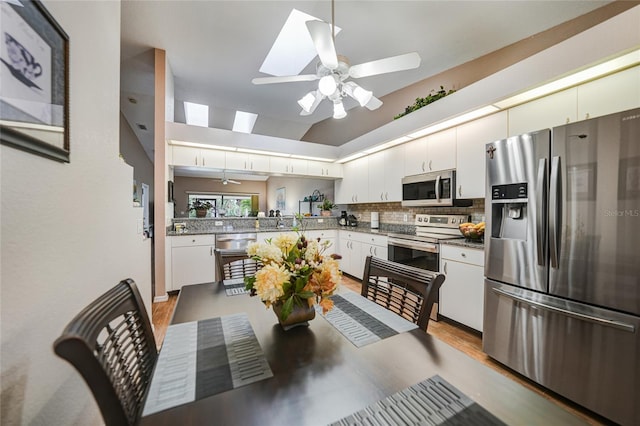 5036 San Rocco Ct, Punta Gorda, FL 33950 - kitchen with a ceiling fan, vaulted ceiling with skylight, stainless steel appliances, decorative backsplash, and white cabinetry