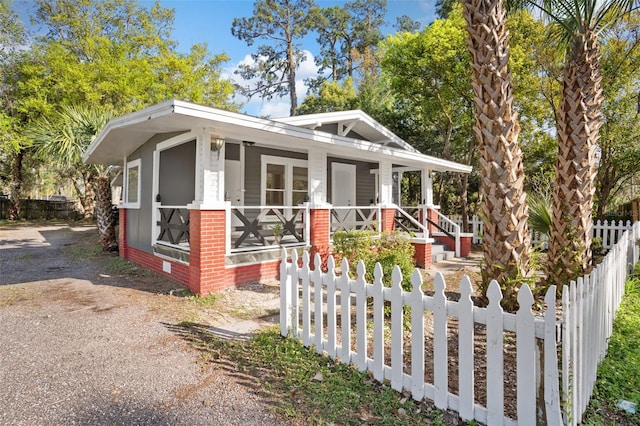 view of front of property featuring brick siding, covered porch, and a fenced front yard