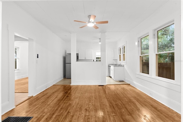 unfurnished living room featuring visible vents, a ceiling fan, baseboards, and light wood finished floors