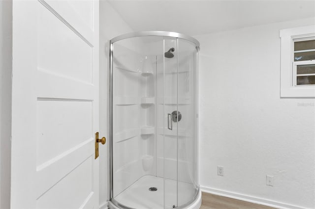 full bathroom with a stall shower, baseboards, and wood finished floors