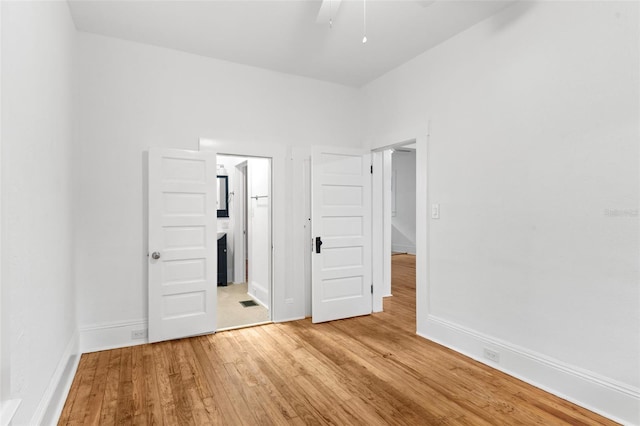 unfurnished bedroom featuring light wood-style flooring, ensuite bath, and baseboards